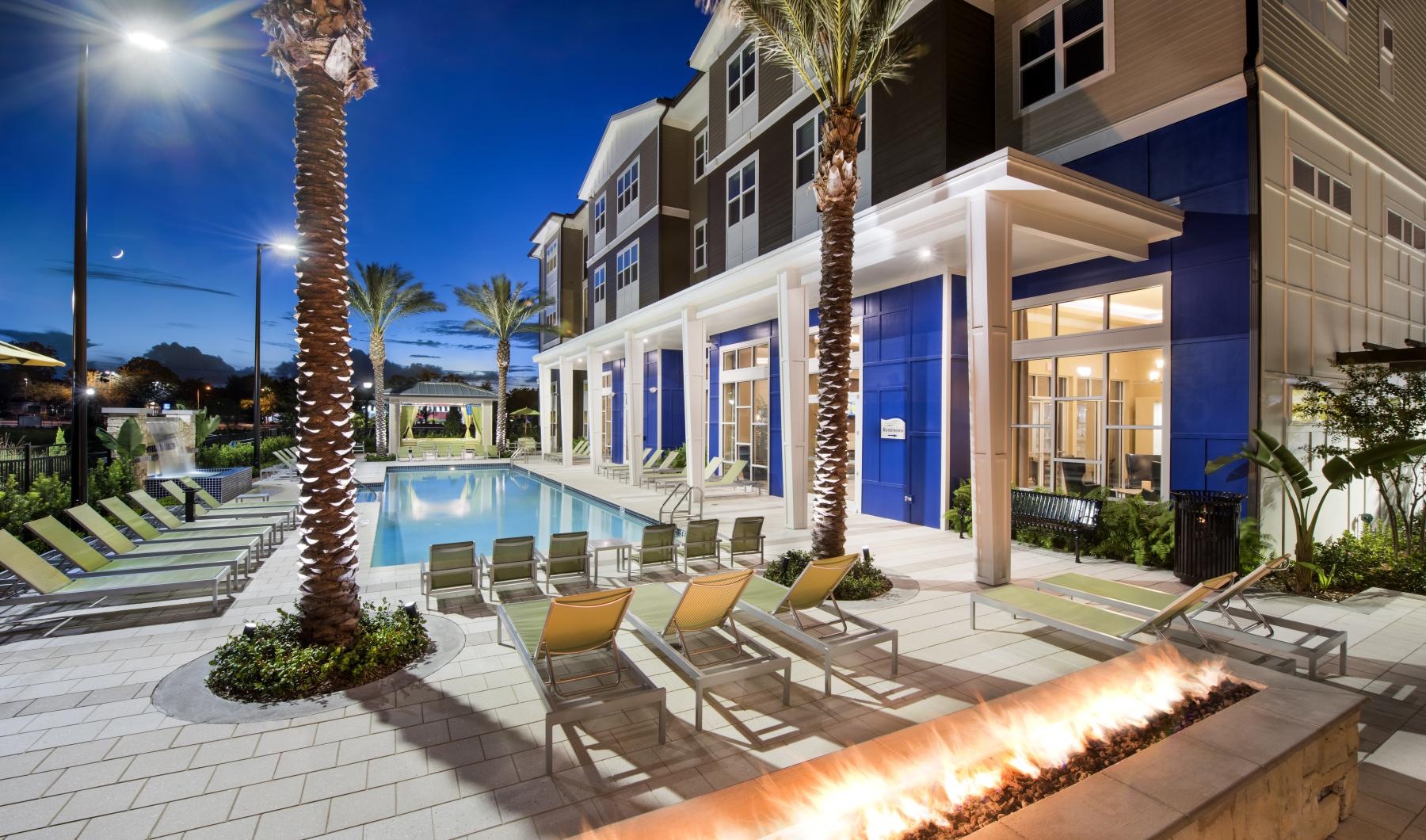 a swimming pool with lounge chairs and a fire pit